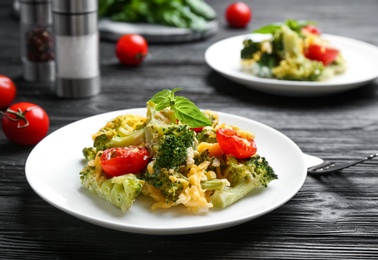 Photo of Tasty broccoli casserole served on black wooden table