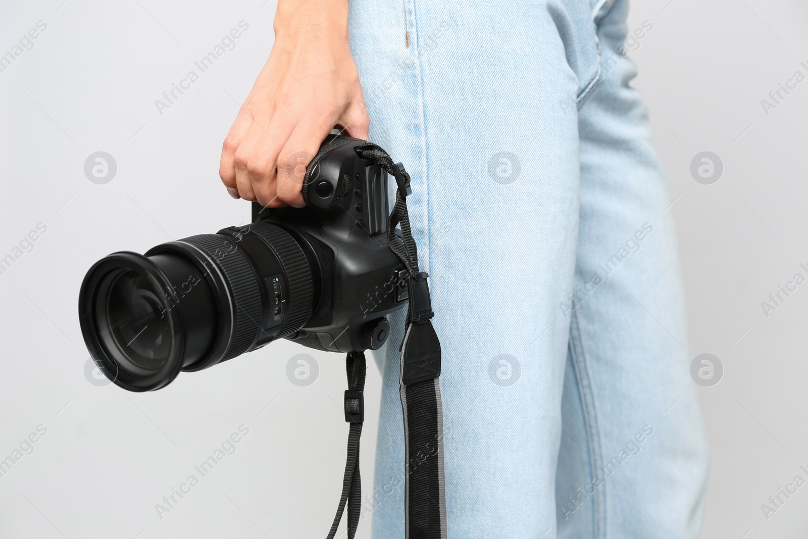 Photo of Professional photographer with modern camera on light background in studio, closeup
