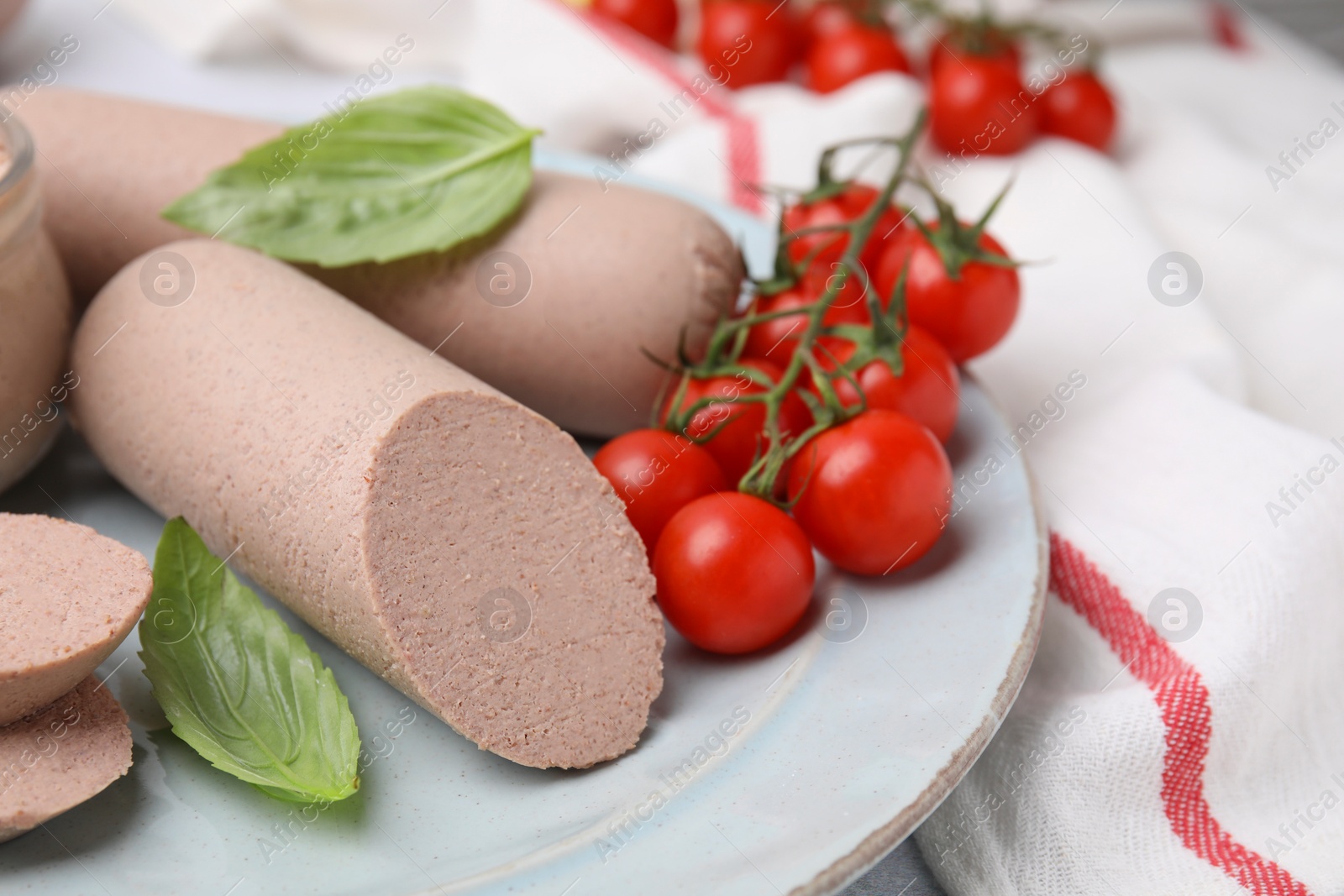 Photo of Delicious liver sausages and cherry tomatoes on plate, closeup