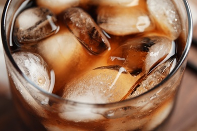 Photo of Glass of tasty refreshing cola with ice cubes, closeup