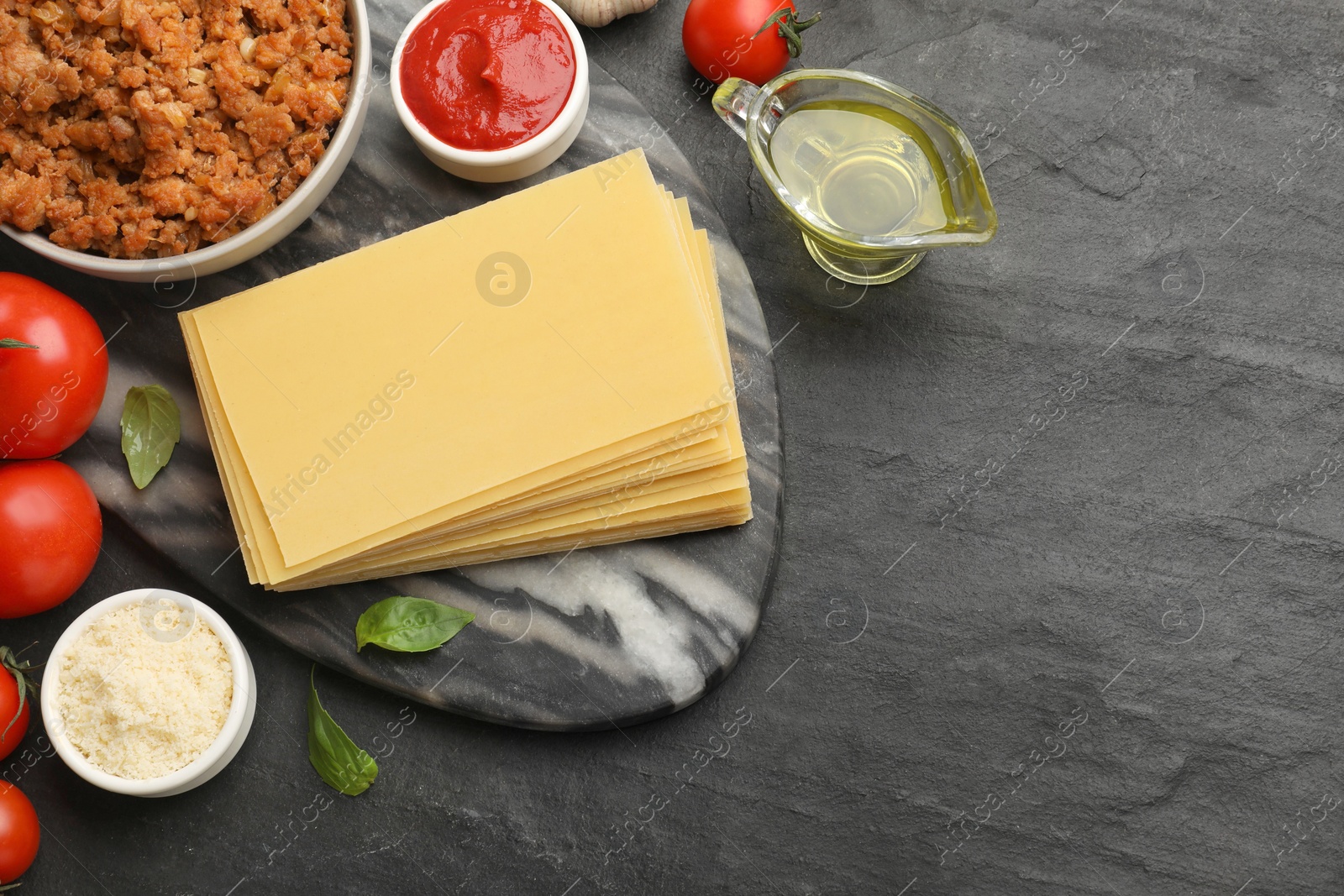 Photo of Flat lay composition with products for cooking lasagna on dark textured table. Space for text