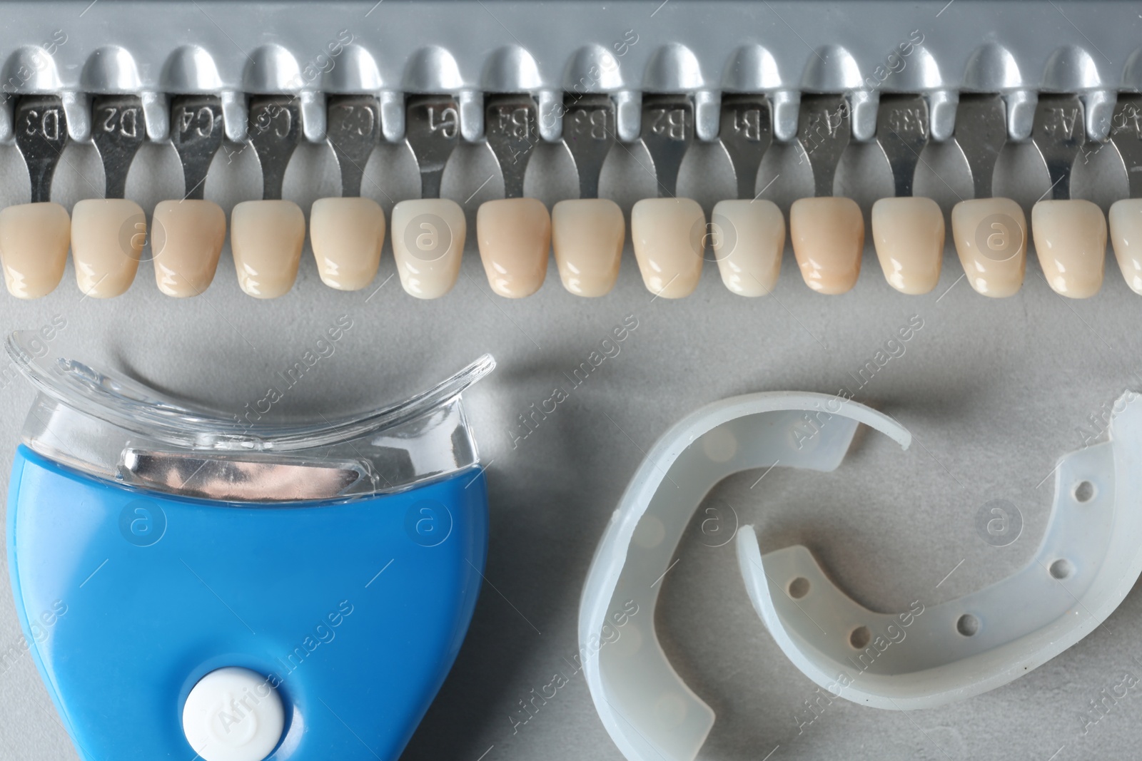 Photo of Teeth whitener, mouth covers and shade guide on grey background, top view