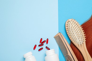 Hair lock, brushes and pills on light blue background, flat lay. Space for text