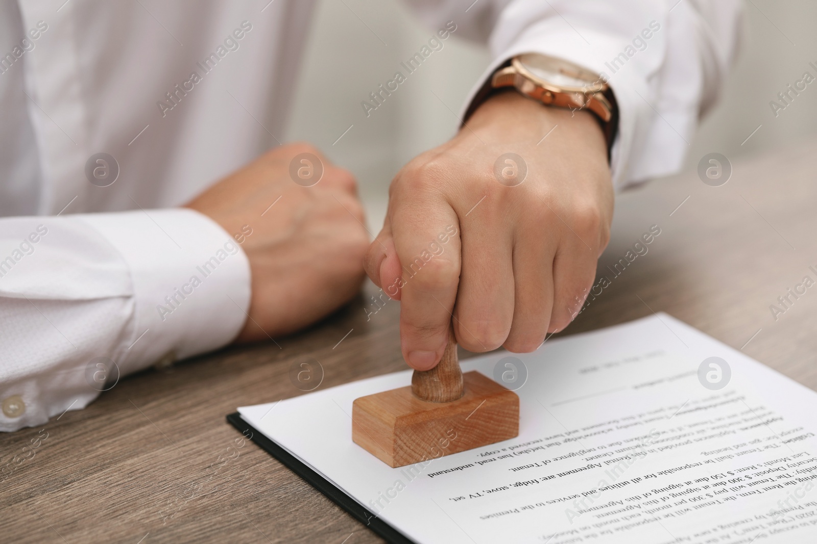 Photo of Man stamping document at wooden table, closeup