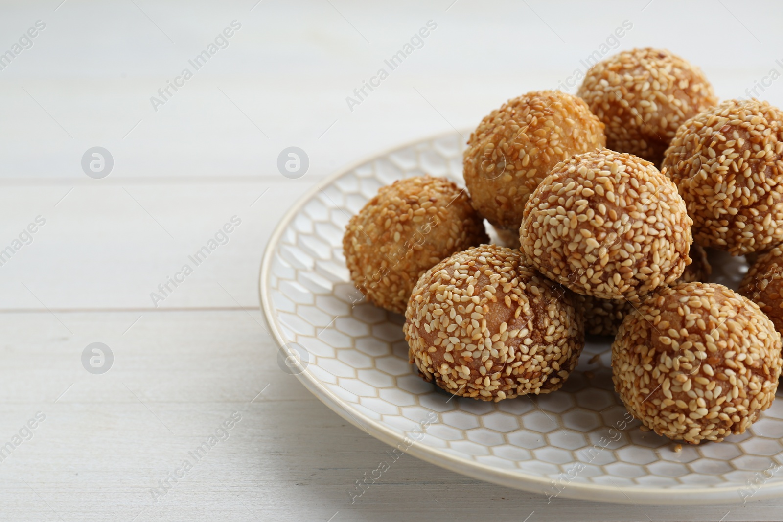 Photo of Delicious sesame balls on white wooden table, closeup. Space for text