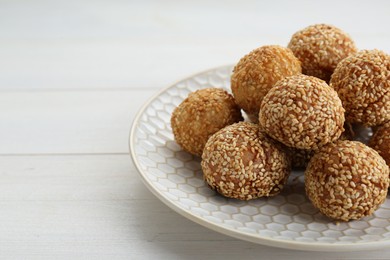 Photo of Delicious sesame balls on white wooden table, closeup. Space for text