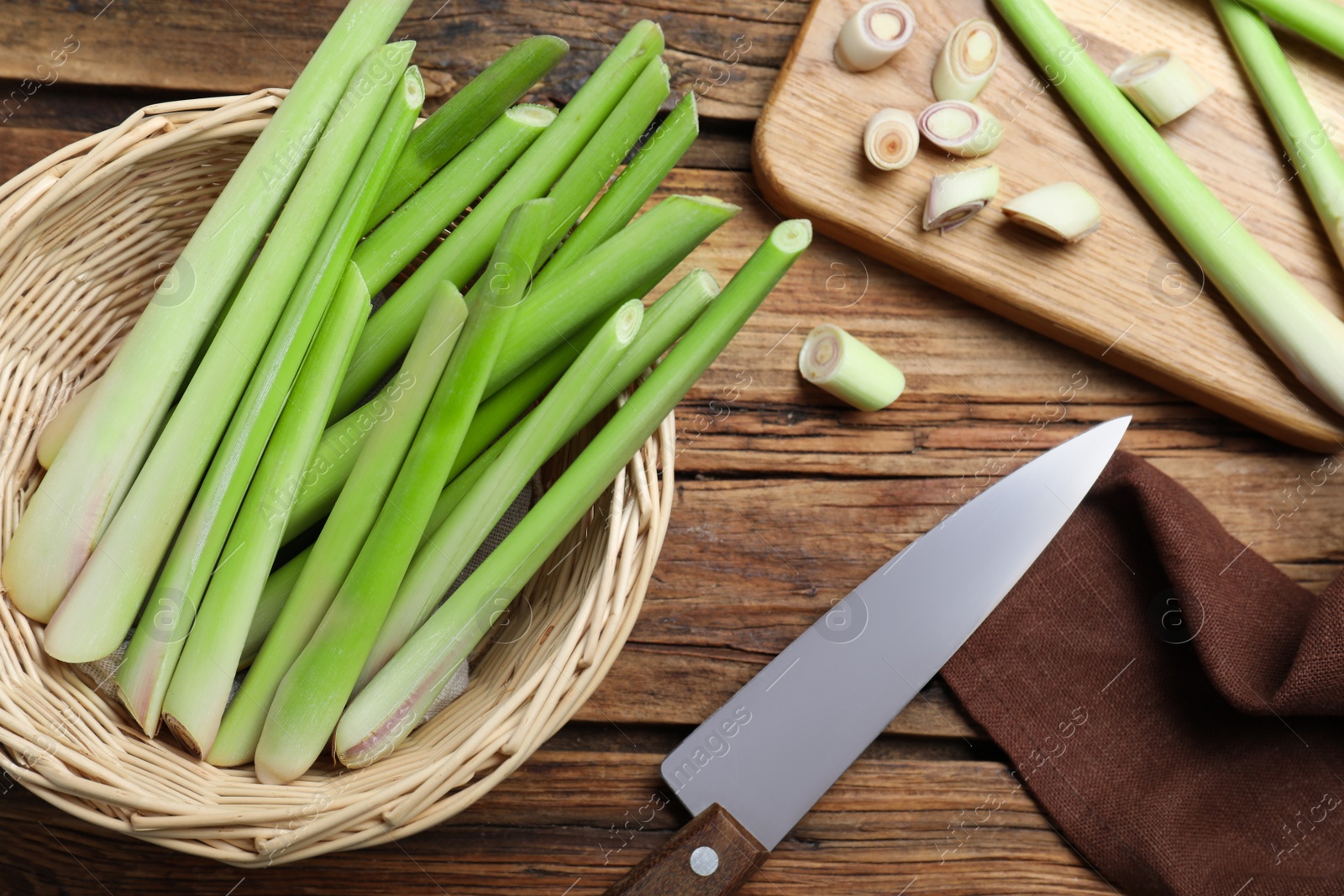 Photo of Fresh lemongrass, knife and cutting board on wooden table, flat lay