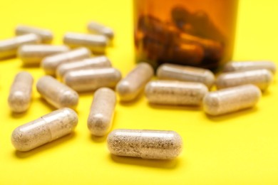 Photo of Many transparent gelatin capsules on yellow background, closeup