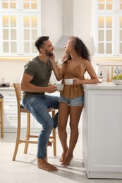 Photo of Lovely couple with cups of drink enjoying time together in kitchen at home