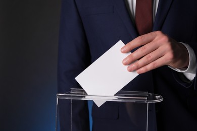 Photo of Man putting his vote into ballot box on dark background, closeup. Space for text