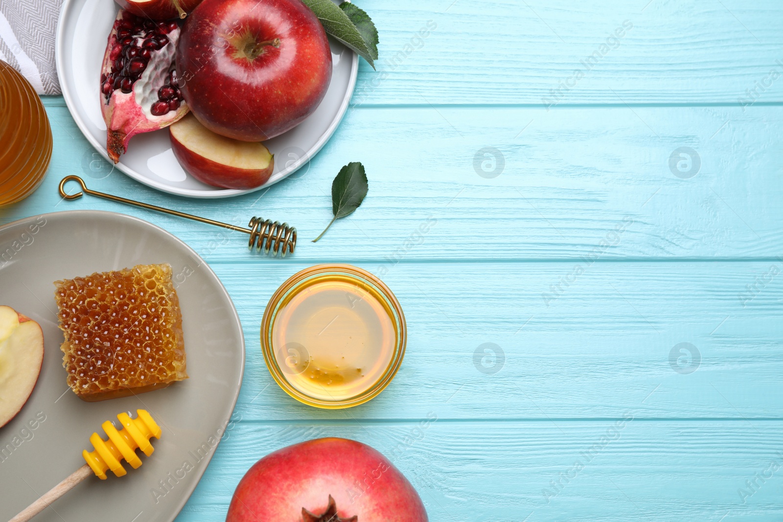 Photo of Honey, apples and pomegranates on light blue wooden table, flat lay with space for text. Rosh Hashanah holiday