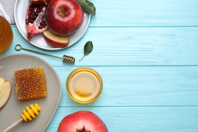 Photo of Honey, apples and pomegranates on light blue wooden table, flat lay with space for text. Rosh Hashanah holiday