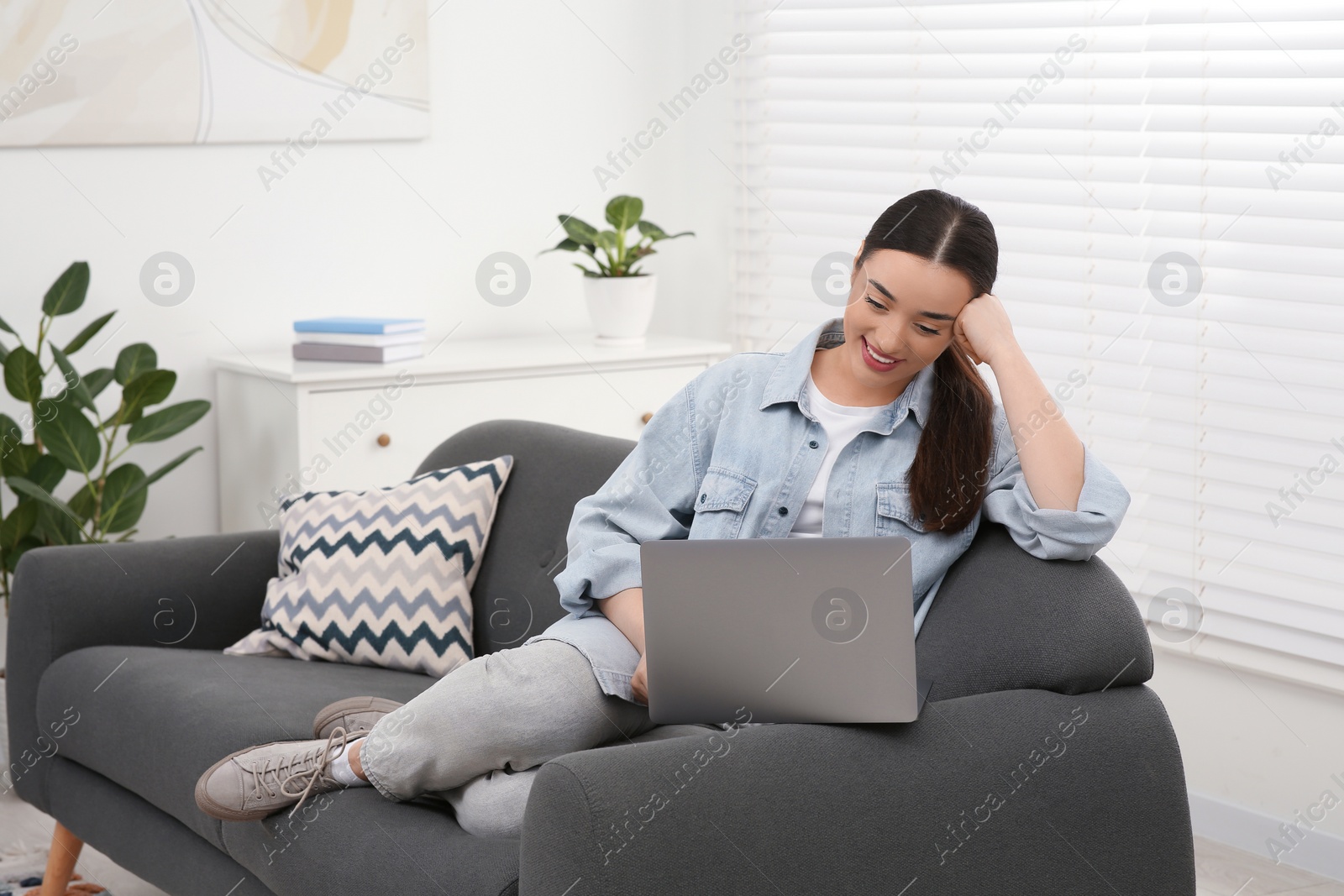 Photo of Woman using laptop on couch at home