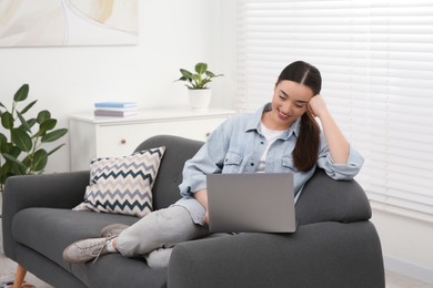 Woman using laptop on couch at home