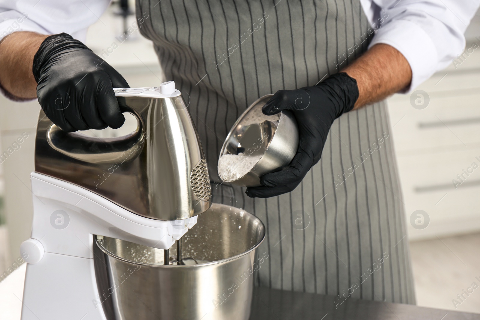 Photo of Male pastry chef preparing dough in mixer at kitchen table, closeup