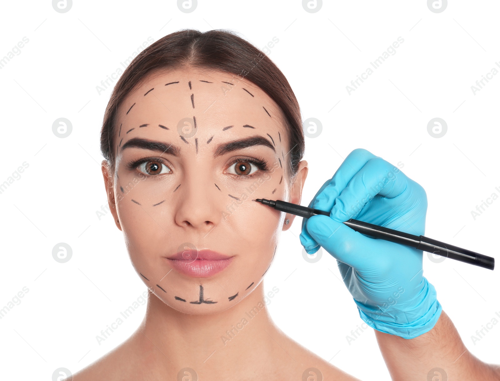 Photo of Doctor drawing marks on woman's face for cosmetic surgery operation against white background