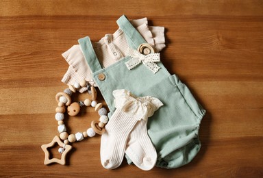 Photo of Children's clothes and toy on wooden table, flat lay