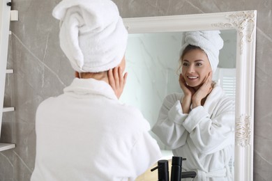 Photo of Beautiful woman looking at herself in bathroom mirror