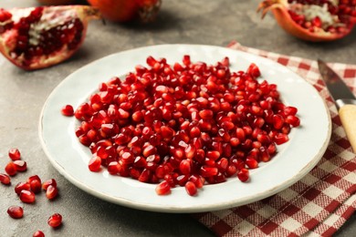 Photo of Tasty ripe pomegranate grains on grey table, closeup