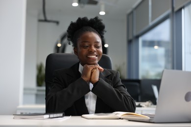 Photo of Happy woman working at table in office. Lawyer, businesswoman, accountant or manager