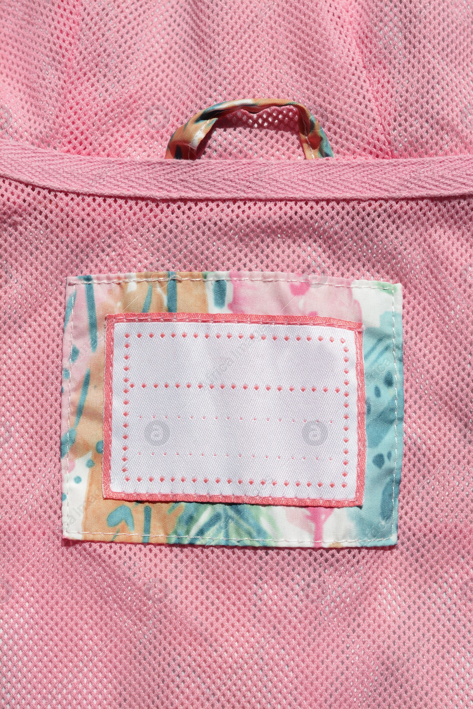 Photo of Clothing label on pink garment, top view