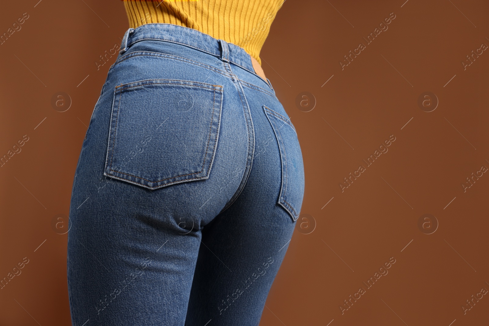 Photo of Woman in stylish jeans on brown background, closeup. Space for text