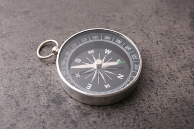 Photo of One compass on grey table, closeup. Tourist equipment
