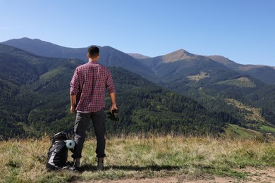 Photo of Tourist with hiking equipment and binoculars in mountains, back view