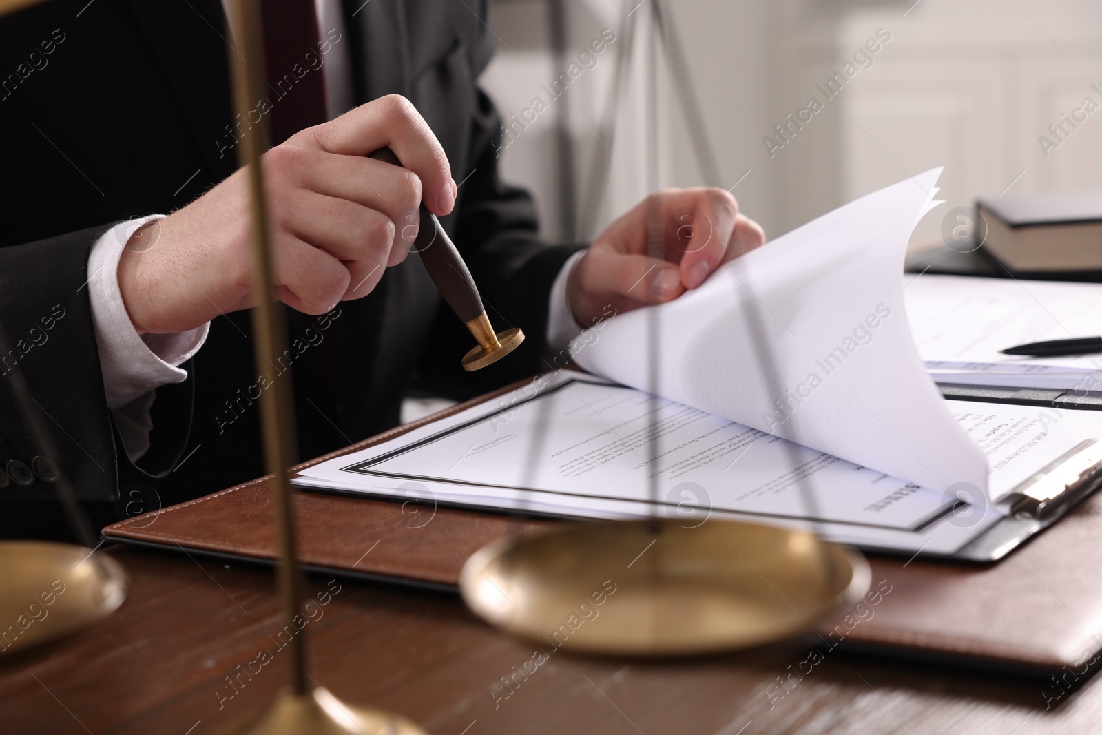 Photo of Notary stamping document at wooden table in office, closeup