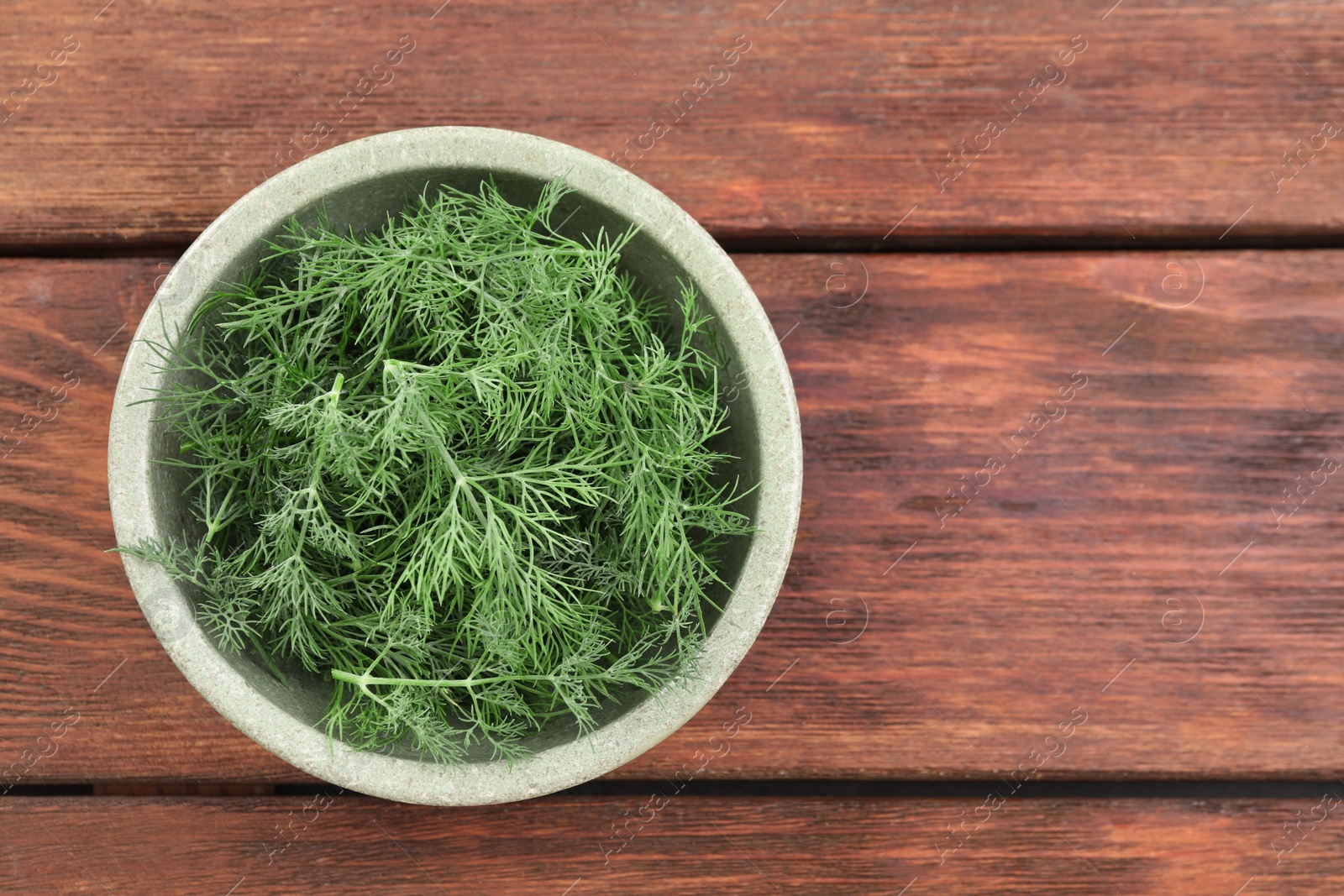 Photo of Bowl of fresh dill on wooden table, top view. Space for text