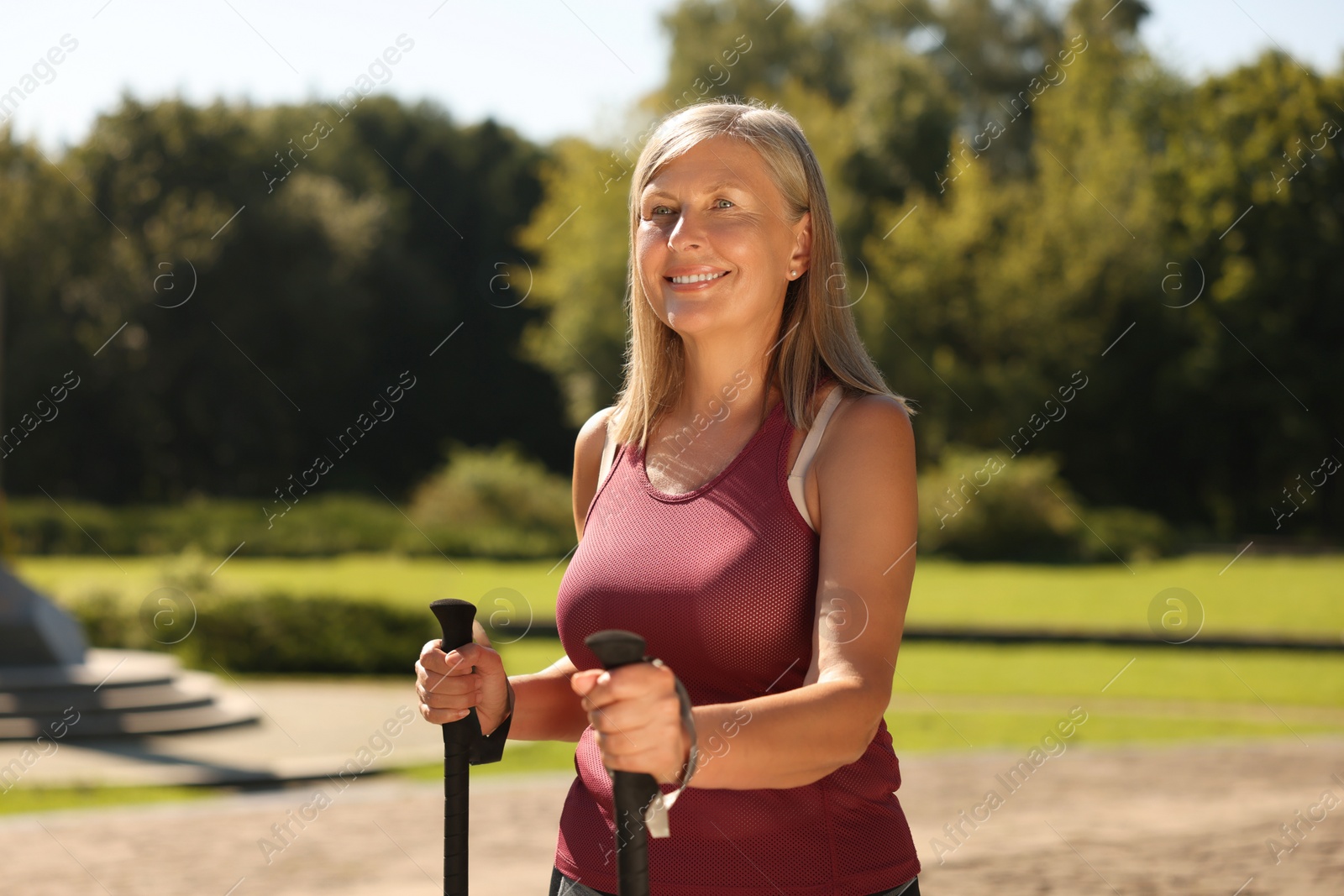 Photo of Happy woman with poles for Nordic walking in park