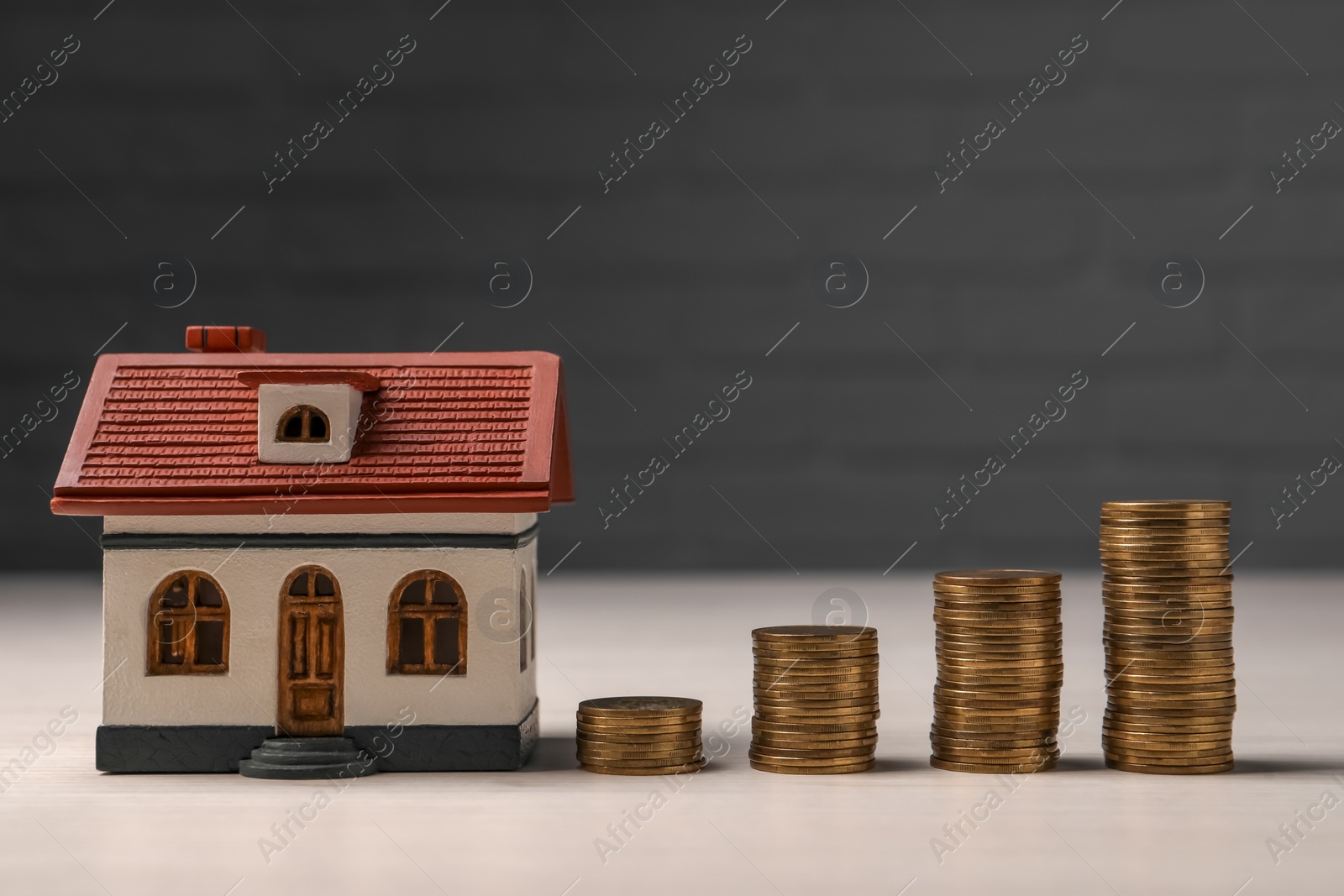 Photo of Mortgage. House model and coins on light table
