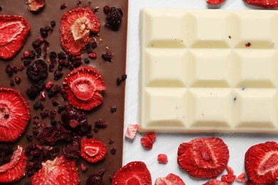 Photo of Different chocolate bars with freeze dried fruits on white wooden table, flat lay
