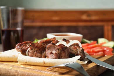 Wooden board with juicy shish kebab, closeup