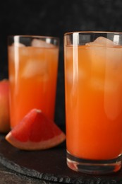 Photo of Tasty grapefruit drink with ice in glasses on table, closeup