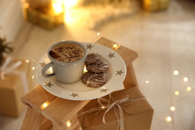 Photo of Tasty hot drink, chocolate cookies and Christmas lights indoors. Space for text