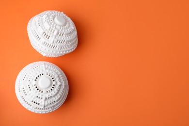 Photo of Laundry dryer balls on orange background, flat lay. Space for text
