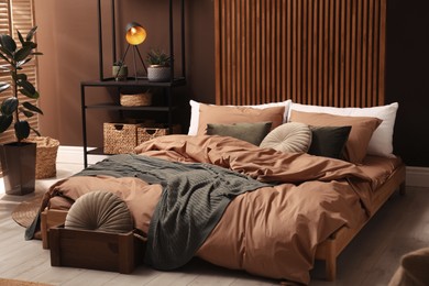 Stylish room interior with large bed near brown wall