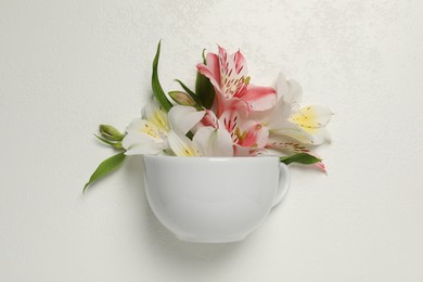 Photo of Composition with cup and beautiful flowers on light background