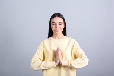 Photo of Young woman meditating on grey background. Stress relief exercise