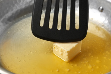 Frying pan with melting butter and spatula, closeup