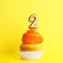 Photo of Birthday cupcake with number two candle on yellow background