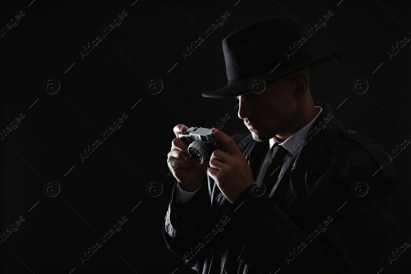 Photo of Old fashioned detective with camera on dark background. Space for text