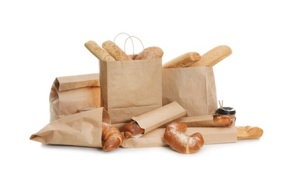 Different fresh bakery products in paper bags on white background