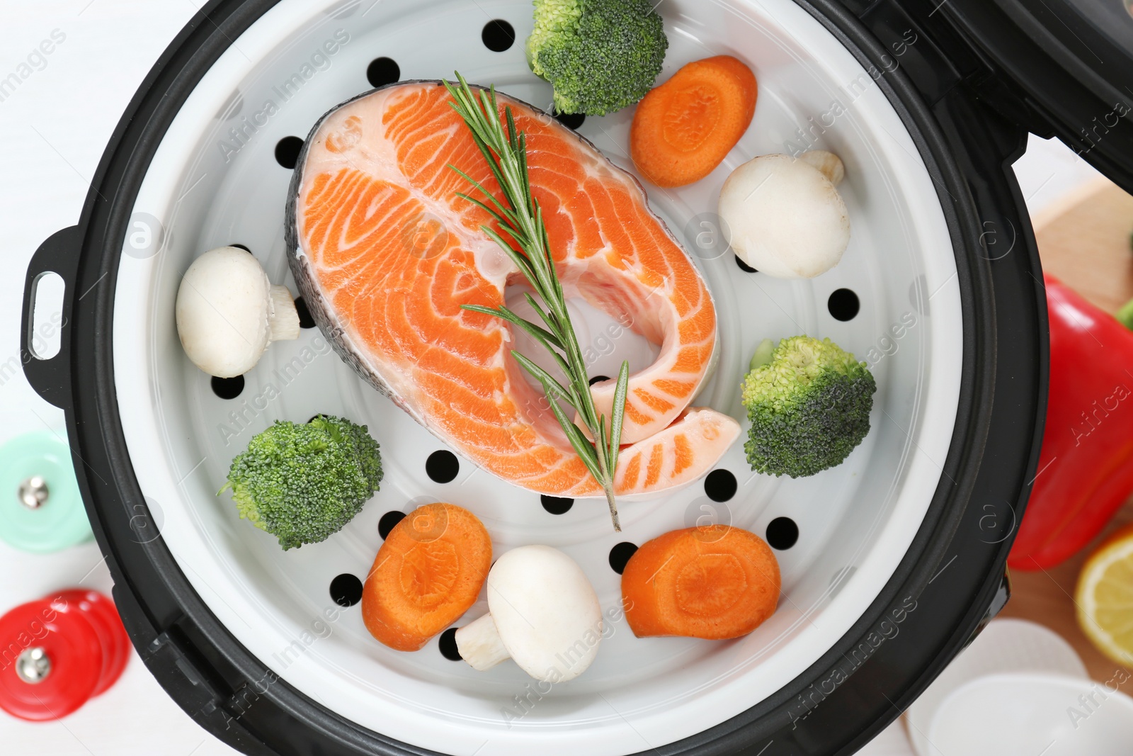 Photo of Salmon steak with garnish in multi cooker on table, top view