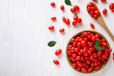 Photo of Flat lay composition with fresh ripe goji berries on white wooden table. Space for text