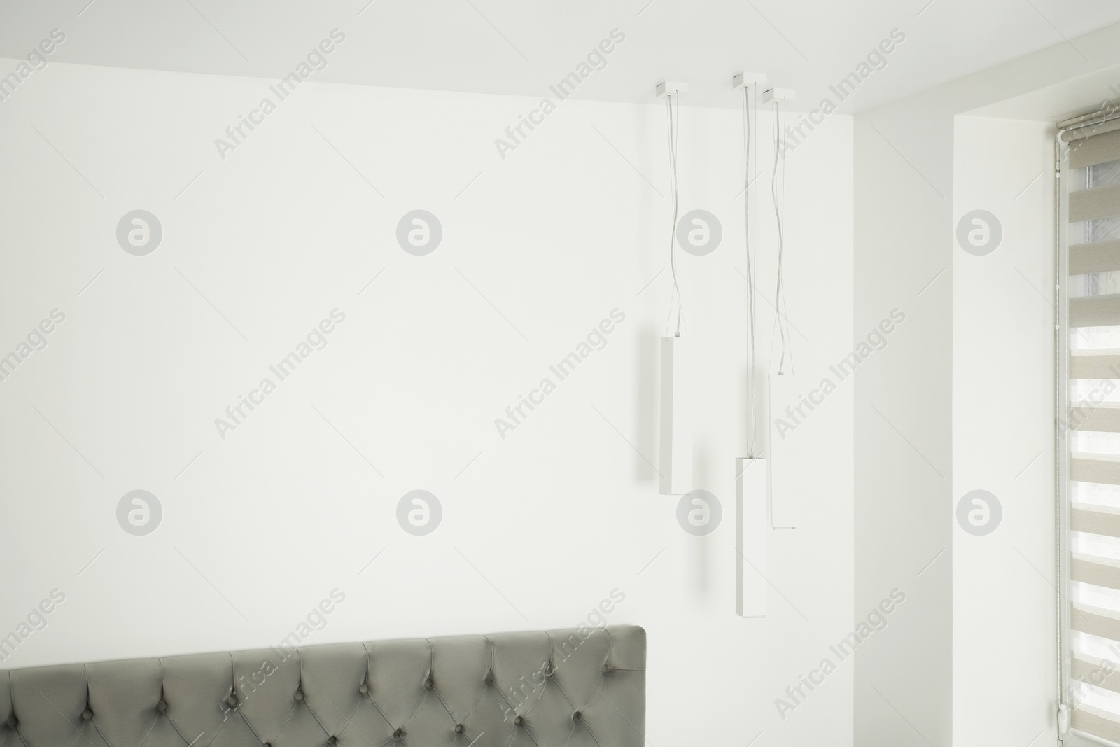 Photo of Stylish lamps hanging in light room. Space for text