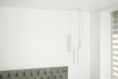 Stylish lamps hanging in light room. Space for text