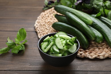 Photo of Fresh ripe cucumbers and basil on wooden table