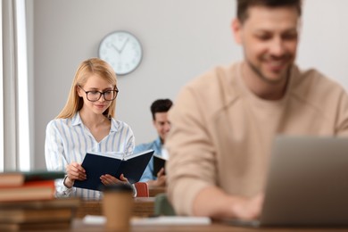 Photo of Young woman reading book at table in library